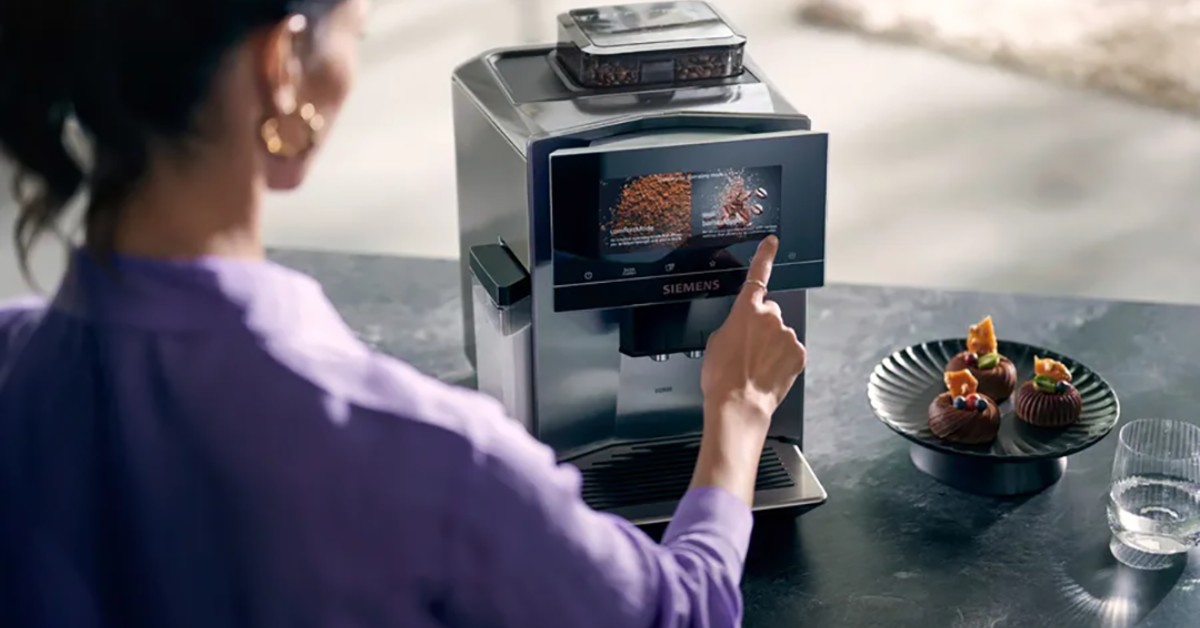 Женщина прикасается к сенсорному экрану полностью автоматической кофемашины Siemens EQ900